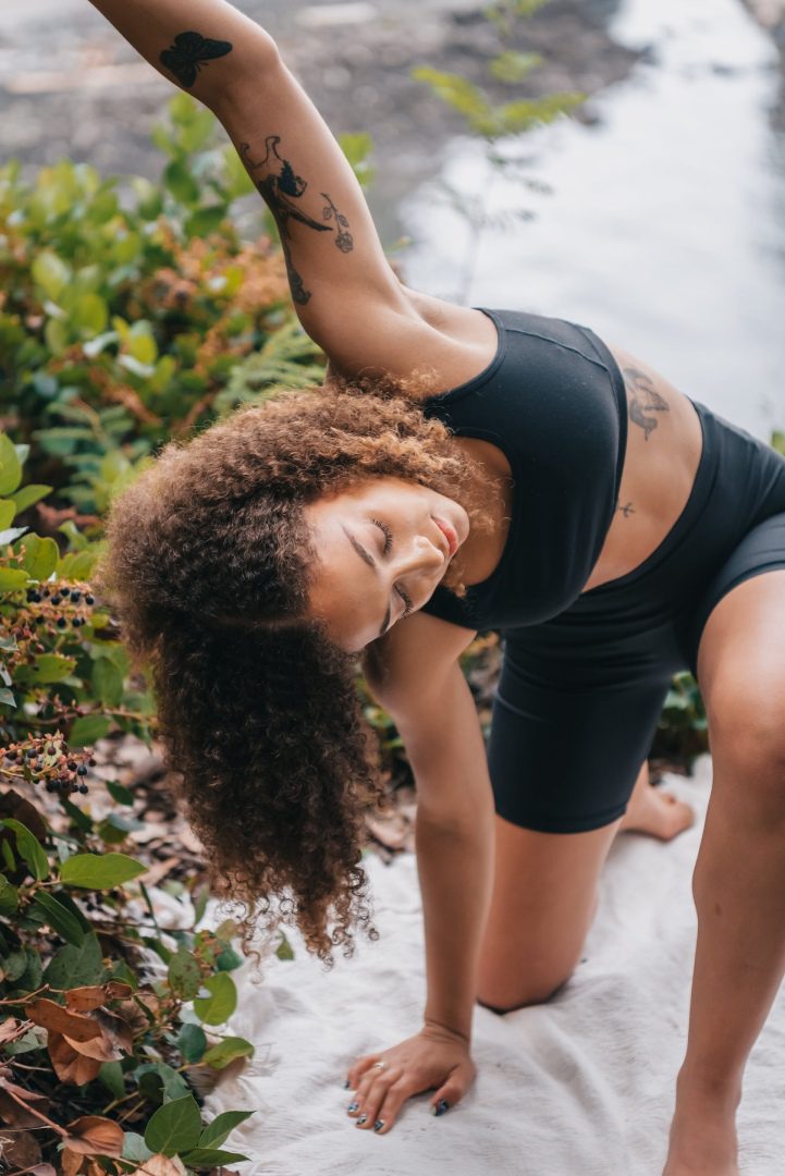 A woman in black shirt and shorts doing yoga.